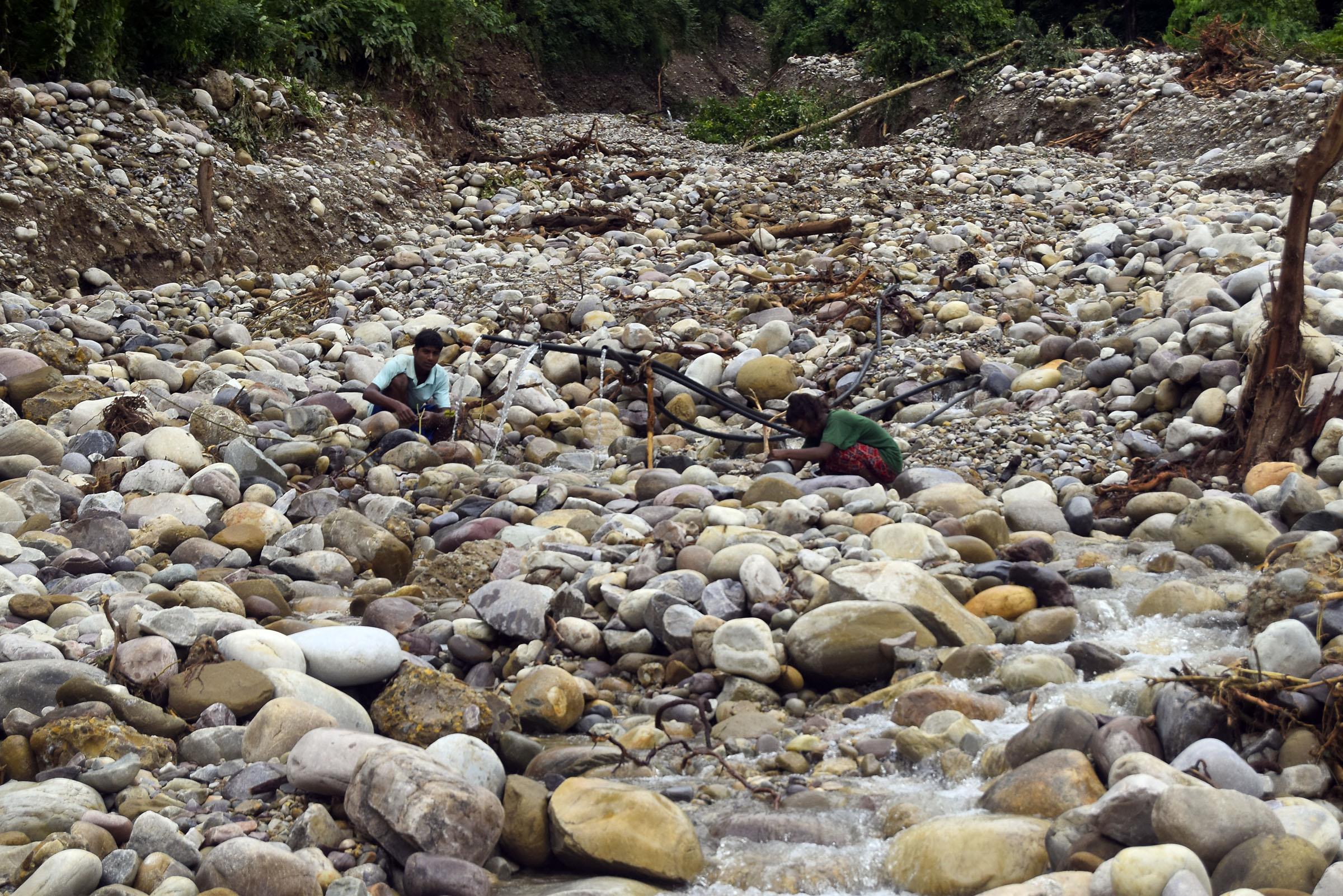 खानेपानीको जाहोः सुर्खेतको पञ्चपुरी नगरपालिका-१०, गल्फामा बाढीले खानेपानीको मुहान बगाएपछि खोला बगरमा पानी भर्दै स्थानीय।