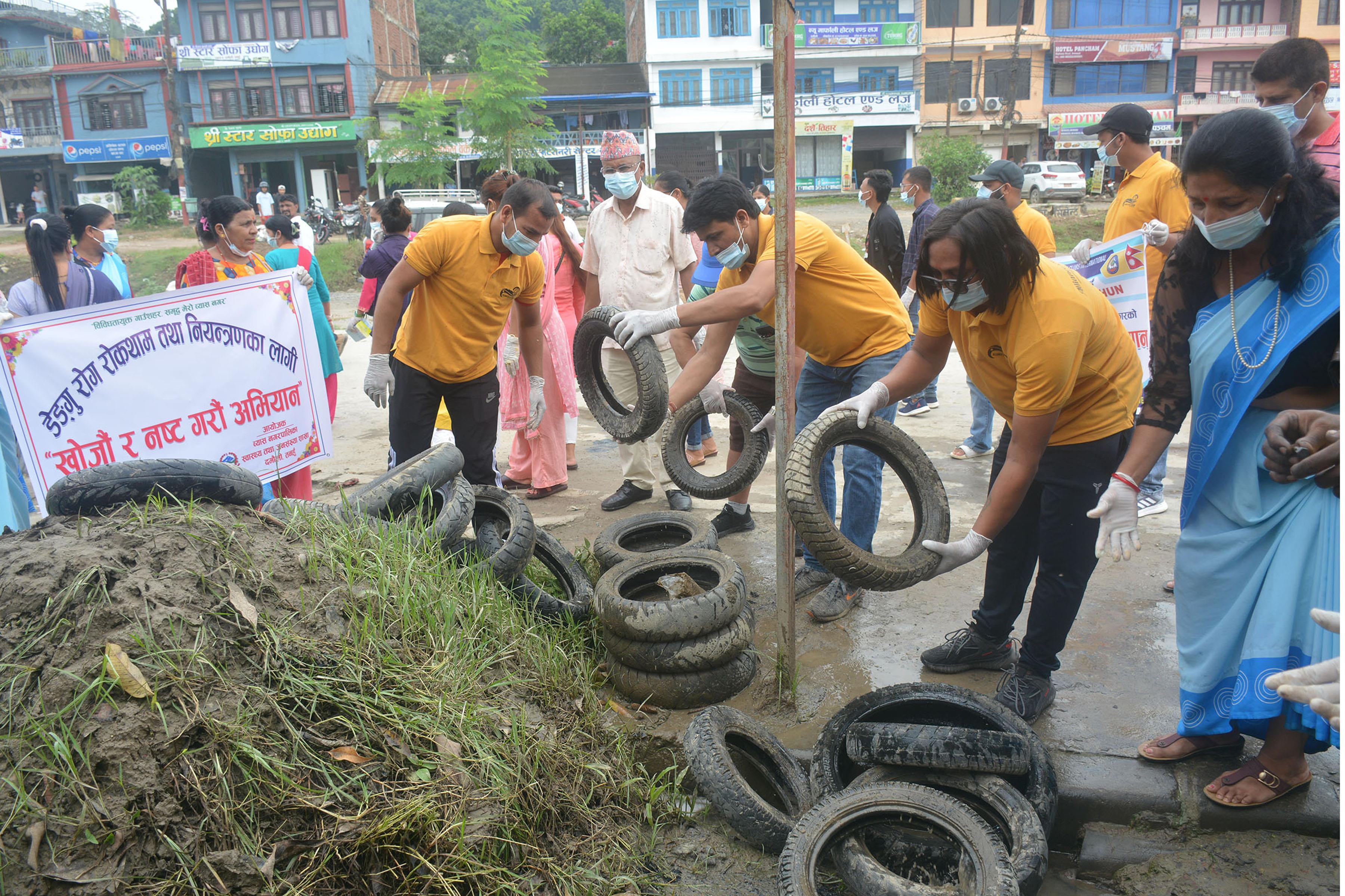 स्वास्थ्य सचेतना: डेङ्गु रोकथाम तथा नियन्त्रणका लागि तनहुँको व्यास नगरपालिकाद्वारा असोज ८ गते आयोजित ‘खोज र नष्ट अभियान’ अन्तर्गत एक मोटरसाइकल वर्कसपमा टायरमा जम्मा भएको पानी फाल्दै नगरप्रमुख वैकुण्ठ न्यौपानेलगायत।